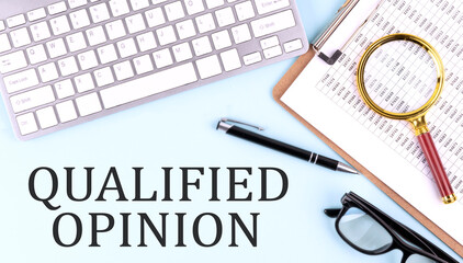 QUALIFIED OPINION text on blue background with keyboard and clipboard, business concept
