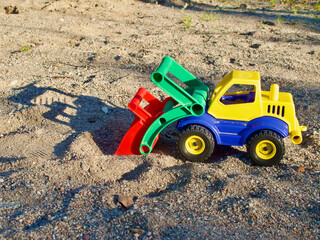 Plastic toy truck with its shadow in the sandbox at childrens playground outdoors in summer.