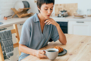 Woman sitting in the kitchen having breakfast.