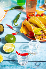 Mexican tequila shots with lime and hot red chili with traditional food corn tacos on the background