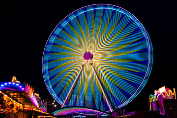 Ferris wheel on a german funfair “Kirmes“ or „Jahrmarkt“ at dark night with many colorful...