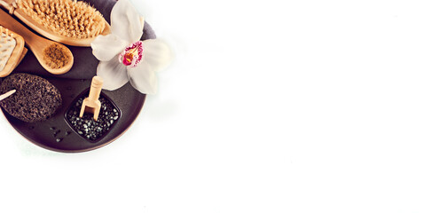 Spa treatment concept. Flat lay composition with massage brushes, pumice stone, black salt, orchid flower