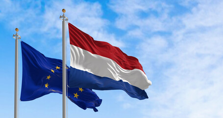 Netherlands and the European Union flags waving in the wind on a clear day