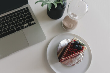 Top view of a delicious cake next to a sleek laptop computer on a white background