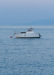beautiful blue mediterranean sunset with and small white anchored fishing boat