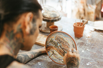 Man painting on clay plate in workshop