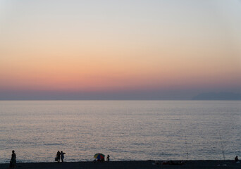 Fototapeta premium Tourist silhouette walking on the beach with orange and pink sunset landscape at background