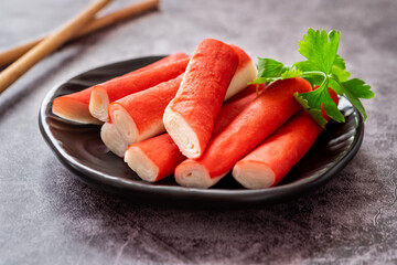 Fresh crab sticks on black plate