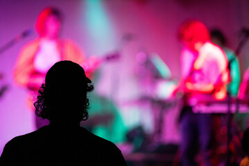 Band playing music and a gig in a venue, close up of a rock band playing guitars and instruments.