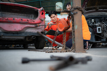 Fototapeta premium To return the automobile body to its former shape, an auto repair mechanic uses a machine to pull the car body caused by a heavy collision until it is deformed.