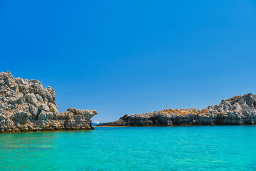 Fototapeta premium St. Paul's Bay near the city of Lindos, clear blue sky and emerald sea, Rhodes island, Greek islands of the Dodecanese archipelago. Holidays and travel around the islands
