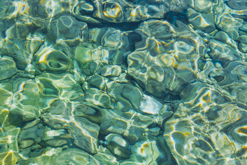 Blurred background of transparent clear water in the sea bay of the Aegean Sea glistens in the sun, idea for a background or postcard