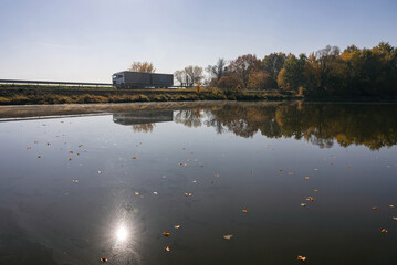 Truck goes on the road in autumn. car transport . Truck with semi-trailer in gray color.  Transport truck drives in autumn by the lake.