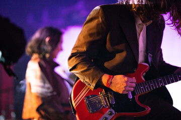 Band playing music and a gig in a venue, close up of a rock band playing guitars and instruments.