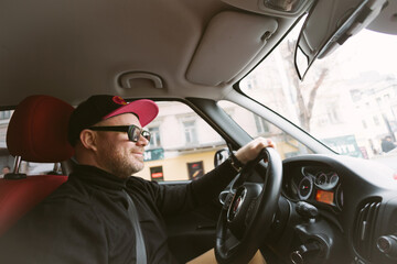 The man with glasses and cap driving car