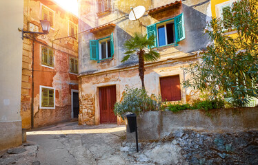 Fototapeta na wymiar Lovran, Istria, Croatia. Vintage medieval buildings and houses at narrow lanes of old town. Stone stairs, wooden doors windows. Sunny evening time