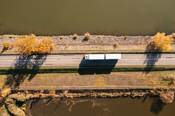 Truck goes on the road in autumn. car transport . Truck with semi-trailer in gray color.  Transport truck drives in autumn by the lake.