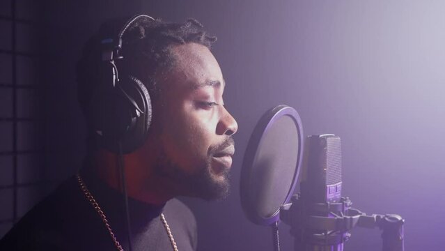 black pop singer is performing song in professional recording studio, portrait of talented musician