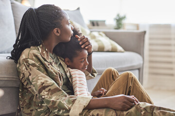 Young mother in camouflage enjoying the time with her little daughter at home