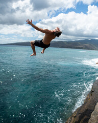 Man cliff jumping off Spitting Cave on Oahu, Hawaii. High quality photo
