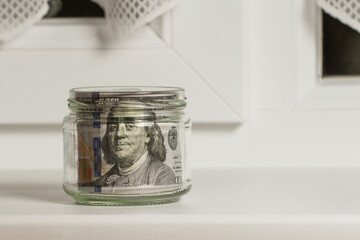 Savings, hundred-dollar bills in a bank near the window of the house.