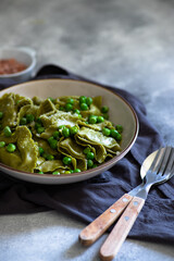 Homemade Italian tortellini with ricotta and spinach served with green pea sauce. A dish of classic Italian cuisine. Tortelloni di ricotta e spinaci. Close-up, selective focus