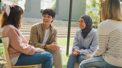 Small Asian group of people sit in a close circle and talk to a therapist in park. Smile people sharing story happy speak diverse people sitting in circle at group therapy session with psychologist. - Powered by Adobe
