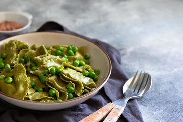 Foto op Canvas Homemade Italian tortellini with ricotta and spinach served with green pea sauce. A dish of classic Italian cuisine. Tortelloni di ricotta e spinaci. Close-up, selective focus © Daria Mladenovic