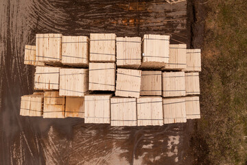 Drone footage piles of lumber in sawmill during summer day.