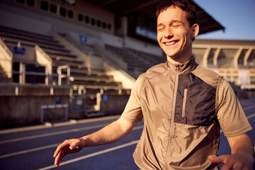 Young man laughing on a running track outdoors