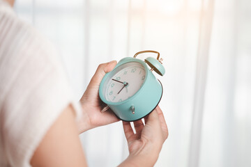 Woman's hand setting the time at the clock to set a reminder or set an alarm