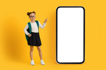 Check This. Little Schoolgirl Pointing At Huge Blank Smartphone With White Screen