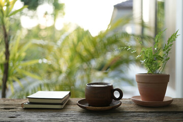 spiral notebook and wooden coffee cup and Victoria Fern pot on wooden table with greenery scene