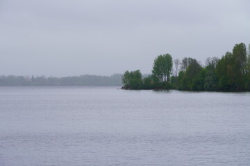 Rainy cloudy  spring day on big lake with small land with trees