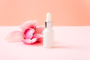 Obraz na płótnie Canvas Face serum and magnolia flower on pink background. Skin care, natural cosmetics concept. Closeup