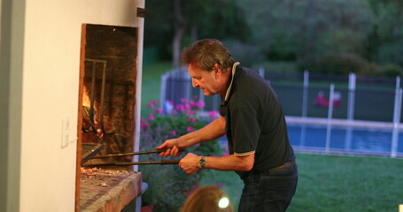 Candid older man preparing BBQ. Casual senior person preparing fire meal