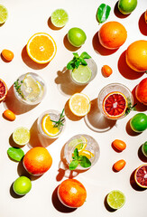 Gin tonic citrus and herb cocktails set, top view. Assortment of summer drinks for cocktail party. Light beige background, bright fruits, hard light, shadow pattern