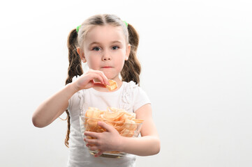 Little girl takes chips snacks with lard from a bowl and eats them, portrait on a white background and copy space