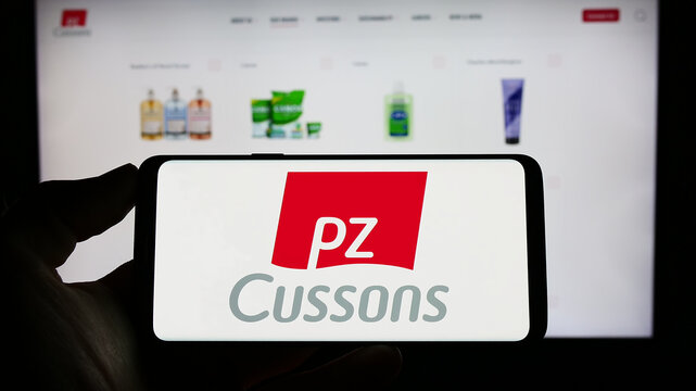 Stuttgart, Germany - 04-20-2023: Person holding cellphone with logo of British consumer goods company PZ Cussons plc on screen in front of webpage. Focus on phone display.