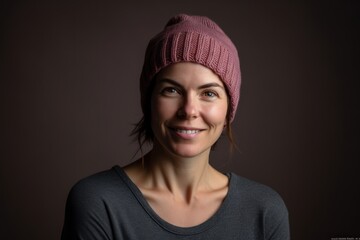 Portrait of a beautiful young woman in a knitted hat on a dark background