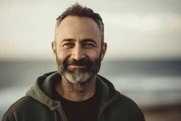 Portrait of handsome mature man with grey beard looking at camera on beach