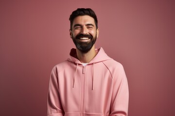 Portrait of a smiling man in a pink hoodie on a pink background