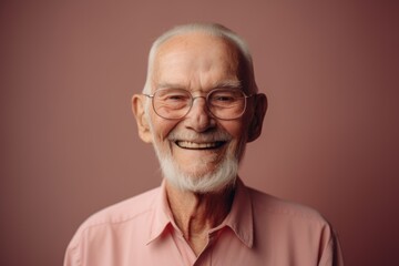 Obraz premium Portrait of a smiling senior man with glasses on a pink background