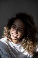 Smiling woman with curly hair and freckles on her face.