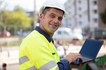 happy architect holding laptop outdoor