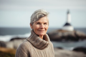 Fototapeta na wymiar Portrait of a senior woman in front of a lighthouse on the coast
