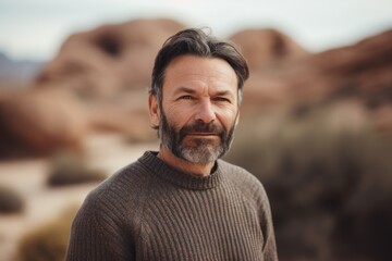 Fototapeta premium Portrait of mature man with grey beard and mustache looking at camera in the desert