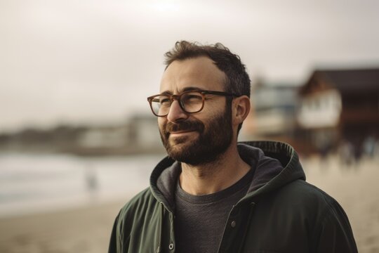 Portrait of a handsome bearded man with glasses on the beach.