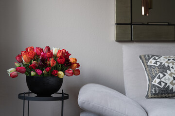 Flowers in a modern home interior. Comfortable grey sofa and coffee table.
