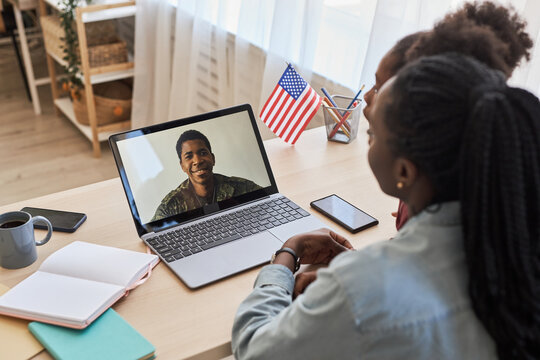 Rear view of family having a video call on laptop with their military dad